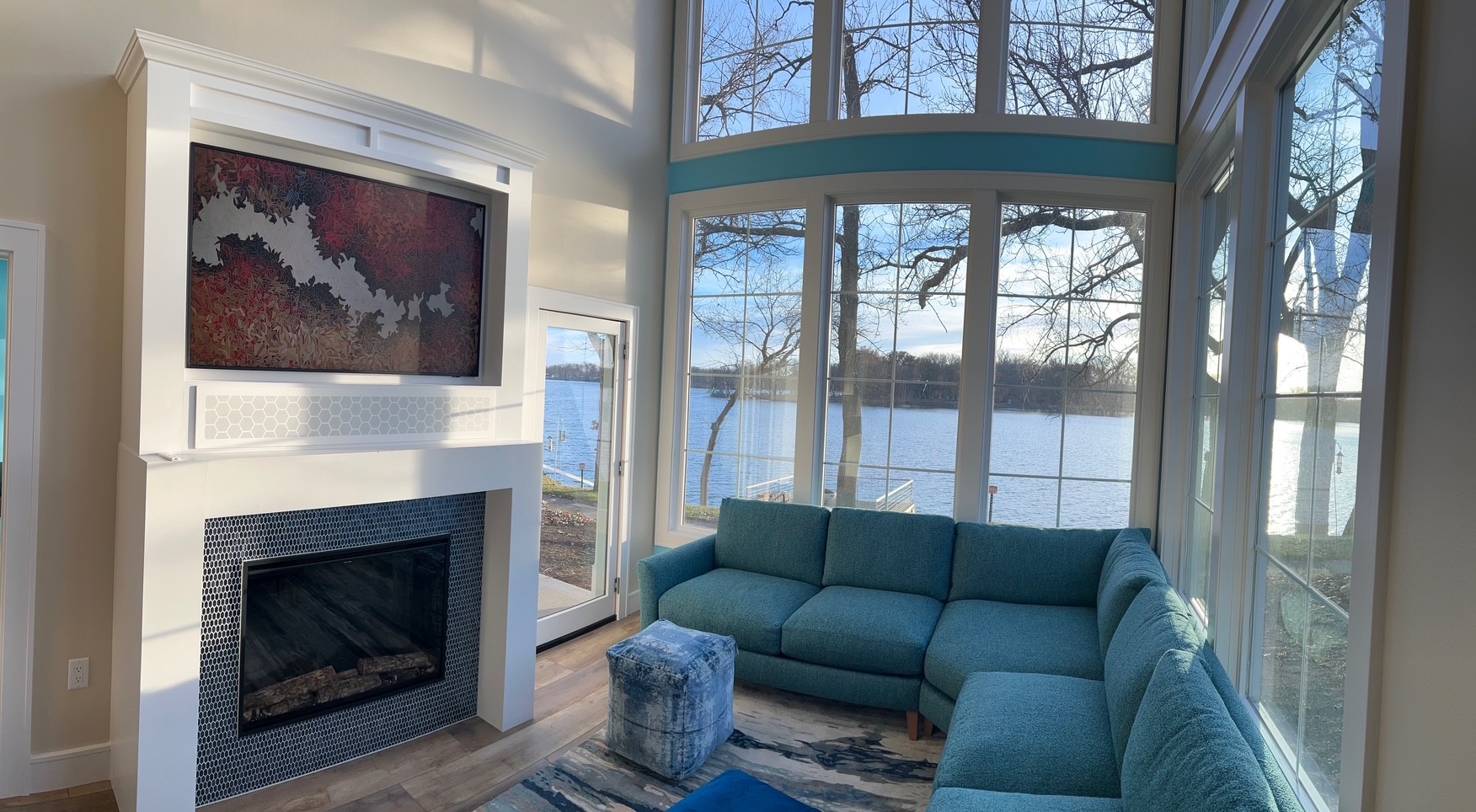 Living room with a television above a tiled fireplace and large windows looking out over the water